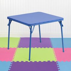 a blue table sitting on top of a multi colored floor covered in foam tiles and plastic mats