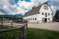 a large white barn sitting on top of a lush green field