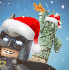 a lego batman christmas card with the statue of liberty in the background and santa hat on