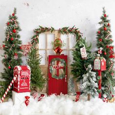 christmas decorations and wreaths are displayed in front of a red door with snow on the ground