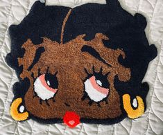 a close up of a rug on a bed with an animal face painted on it