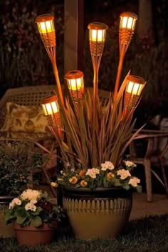 an arrangement of lights in a potted planter with white flowers on the ground