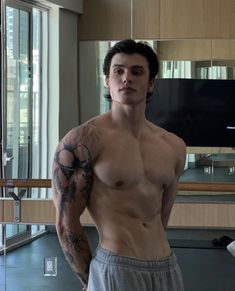 a shirtless man standing in front of a mirror with his hands on his hips