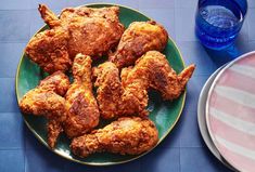 some fried chicken on a green plate next to a glass of water