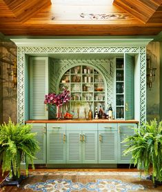 a kitchen with green cabinets and potted plants