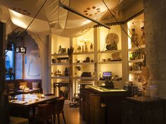 the interior of a restaurant with tables and chairs in front of shelves filled with bottles