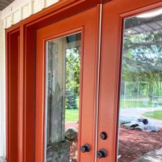 an orange front door with two dogs laying on the ground outside it and one is looking out