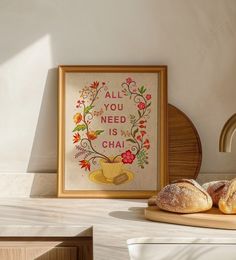 two loaves of bread sit on a cutting board in front of a framed print