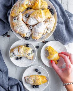 blueberry croissants on white plates with powdered sugar and fresh berries