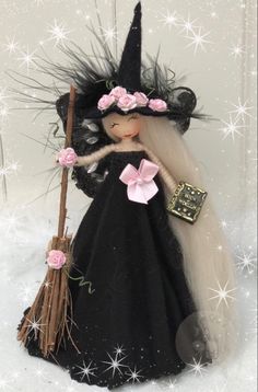 a doll is dressed in black and holding a broom