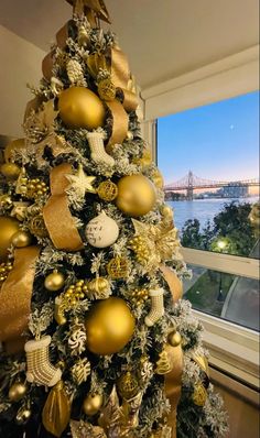 a decorated christmas tree in front of a window with the bay bridge in the background