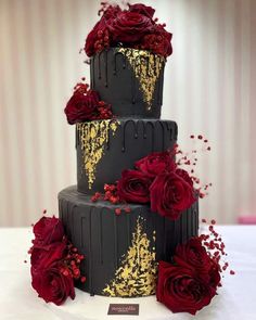 a three tiered cake with red roses on top and gold sprinkles