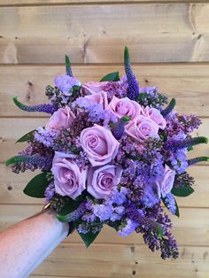 a person holding a bouquet of purple flowers