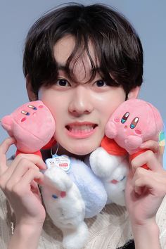 a person holding three stuffed animals in front of their face and smiling at the camera