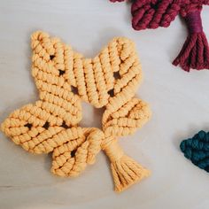 three pieces of yarn are arranged on a table top, one is yellow and the other is blue