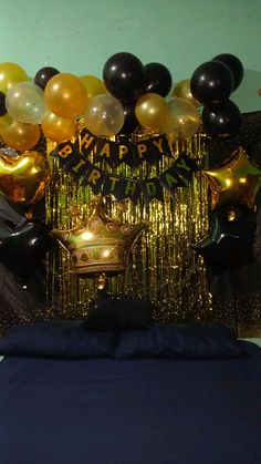 balloons and streamers decorate the backdrop for a party in gold, black and silver