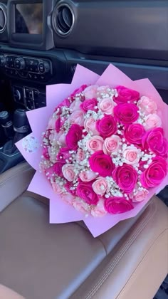 a bouquet of pink and white flowers sitting on top of a car seat next to a steering wheel