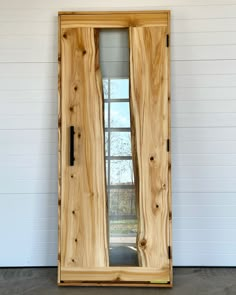 a large wooden door sitting next to a white wall with windows on it's sides