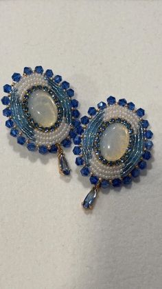 Hand made multi shaded blue seed beads  with  blue and gold lined rhinestone beaded stud earrings with a  opal  center and a blue dangle. Sewn using nylon white thread. Faux leather backing. Earring stud is stainless steel. These were hand crafted by me. All stones and seed beads are not uniform, which gives the overall product a more authentic and "natural" touch. <3 Cheap Blue Beaded Round Earrings, Blue Beaded Earrings Native American, Blue Beaded Clip-on Earrings Gift, Crystal Beaded Earrings With Round Beads, Blue Beaded Round Crystal Earrings, Blue Beaded Crystal Earrings With Round Beads, Blue Drop Earrings With Bead Caps, Blue Dangle Earrings With Bead Caps, Blue Beaded Drop Earrings With Bead Caps