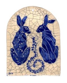 a blue and white tile with two rabbits on it