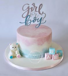 a pink and blue baby shower cake with a teddy bear on the plate next to it