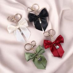 four bow keychains on a white sheet with red, green and black bows