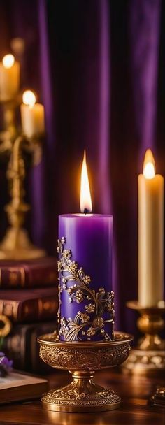 a purple candle sitting on top of a table next to some books and other items