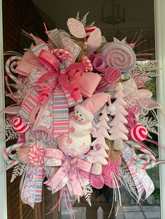 a christmas wreath with candy canes, candies and snowmen on the front door