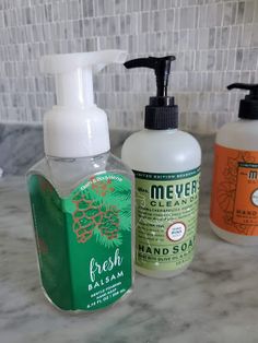 three bottles of hand soap sitting on top of a counter