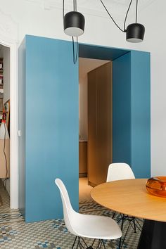 a dining room with blue walls and white chairs