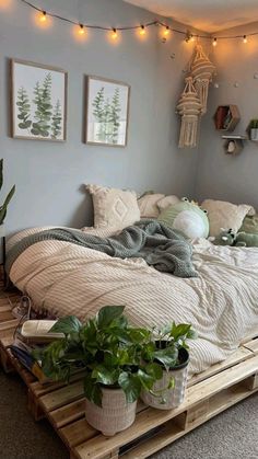 a bed sitting on top of a wooden pallet in a bedroom next to potted plants