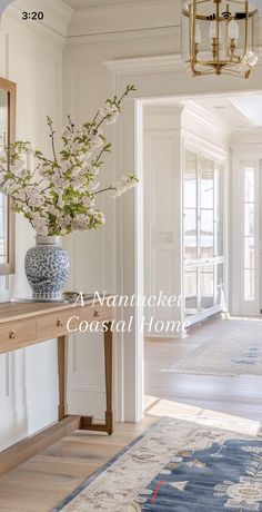 a blue and white vase filled with flowers sitting on top of a wooden table next to a doorway