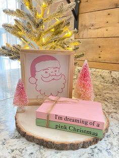 a pink christmas card with a santa clause on it sitting next to two small trees