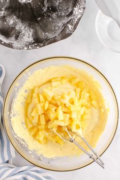 a glass bowl filled with yellow batter next to a blue and white towel