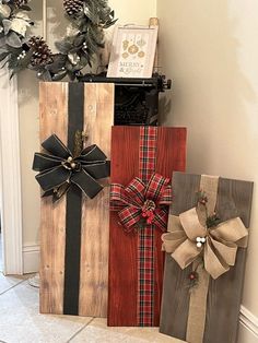 three wooden boxes with bows on them sitting next to a christmas wreath and pine cones