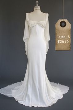 a white wedding dress on display in front of a price tag and mannequin