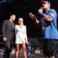 two men and a woman standing in front of a man holding a microphone at a wrestling match