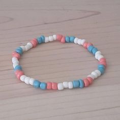 a white and blue beaded bracelet sitting on top of a wooden table