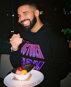 a man with a beard is smiling and holding a piece of cake on a plate