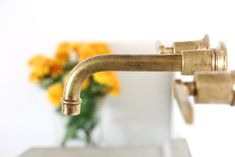 a faucet that is sitting next to a vase with yellow flowers in it