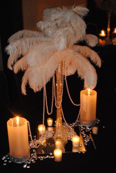 a table topped with candles and a tall palm tree filled with feathers on top of it