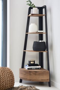 a wooden shelf with books, vases and other items on it next to a window