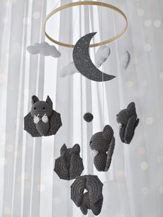 a crocheted bear mobile hanging from a curtain with the moon and stars above it