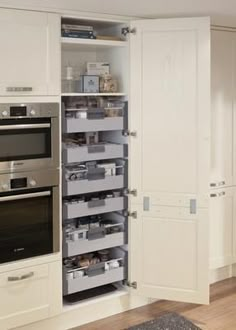 a kitchen with white cabinets and drawers filled with silver items in the cupboards next to an oven