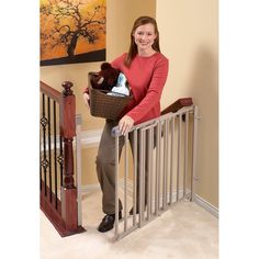 a woman is holding a basket full of baby items in her hand while standing on the stairs