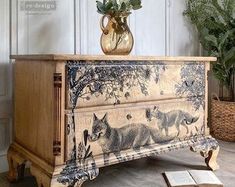 an old dresser with a painting on it and flowers in a vase next to it