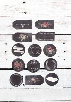 a bunch of tags that are on top of a wooden table with flowers and arrows