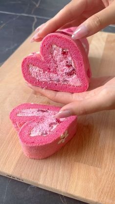 two pink heart shaped pastries on a cutting board with one being cut in half