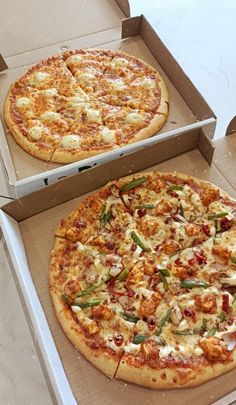 two pizzas sitting in boxes on top of a table