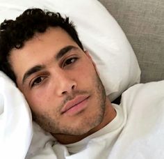 a man laying in bed under a white blanket